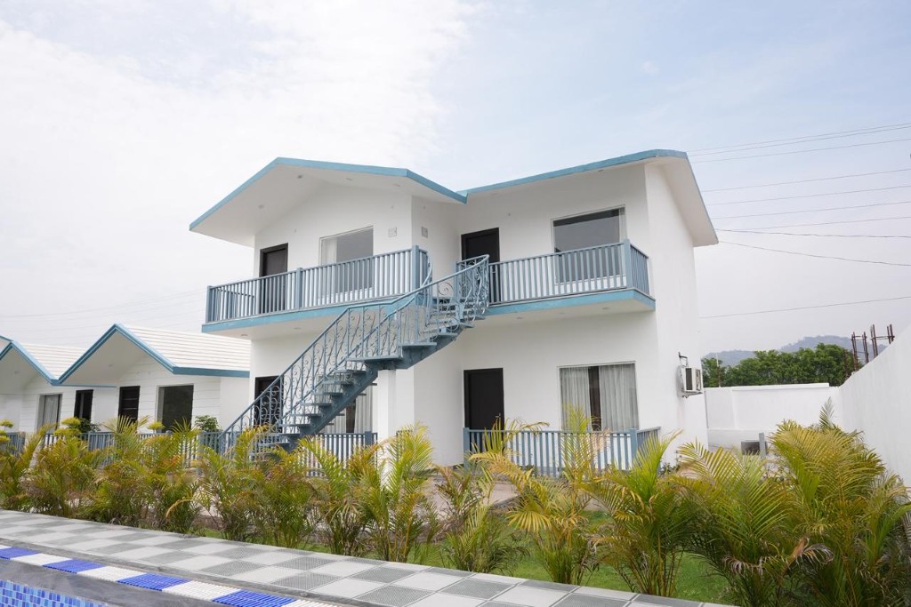 White resort cottages with blue trim and landscaped lawns at Corbett Vantara
